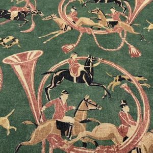 May include: Green fabric with a repeating pattern of riders on horseback, hounds, and hunting horns in shades of brown, red, and black. The design evokes a classic equestrian theme.