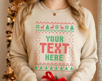 May include: Beige sweatshirt with a festive design. The front features a green and red pattern with the text "YOUR TEXT HERE". The person is holding a wrapped gift with a red bow. The sweatshirt is a cozy, long-sleeved garment.