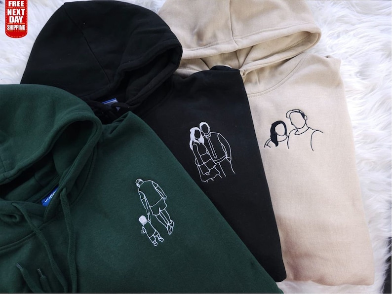 May include: A collection of hooded sweatshirts in black, forest green, and beige. Each hoodie features a white embroidered outline of a person or people. The hoodies have drawstrings and a hood. The text "FREE NEXT DAY SHIPPING" is visible in the upper left corner.