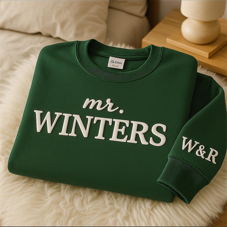 May include: A dark green sweatshirt with the text "mr. WINTERS" in white, stylized lettering across the chest. The sleeve cuff displays the initials "W&R" in white. The sweatshirt is made of a soft material.