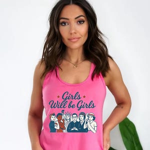 Pode incluir: Top rosa com a frase "Girls Will be Girls" e um gr&aacute;fico de mulheres diversas. O top &eacute; sem mangas e feito de um material macio. O gr&aacute;fico apresenta ilustra&ccedil;&otilde;es de mulheres em v&aacute;rias poses.
