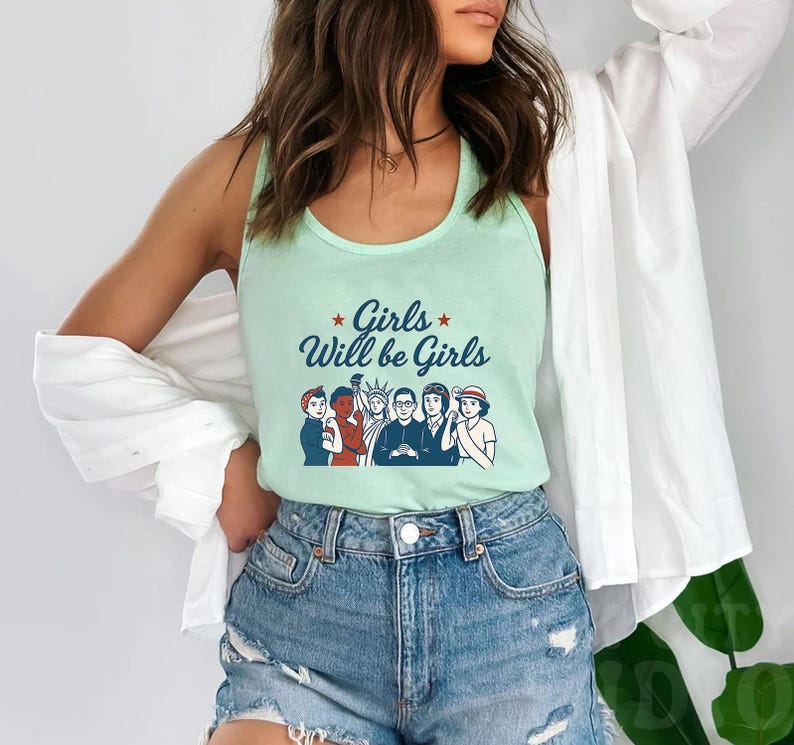 Pode incluir: Uma regata verde clara com o texto "Girls Will be Girls" e um gr&aacute;fico de seis pessoas. A regata &eacute; combinada com shorts jeans. O estilo geral &eacute; casual e confort&aacute;vel.