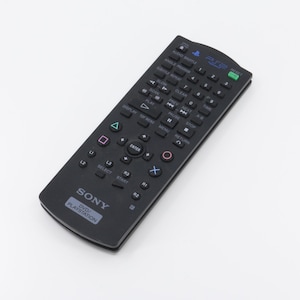 May include: Black remote control for a Sony DVD/PlayStation with buttons for navigation, play, pause, stop, and other functions. The remote has a PlayStation logo and the text "DVD/PLAYSTATION" printed on it.