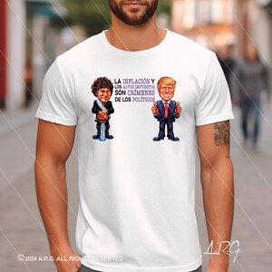 May include: White t-shirt featuring a cartoon illustration of two men. The text on the shirt reads "LA INFLACIÓN Y LOS ALTOS IMPUESTOS SON CRÍMENES DE LOS POLÍTICOS".