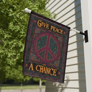 Puede incluir: Una bandera decorativa para exteriores con las palabras "GIVE PEACE A CHANCE" en letras doradas. La bandera presenta un gran símbolo de la paz en un círculo, con un patrón floral detallado en tonos verdes, morados y dorados.