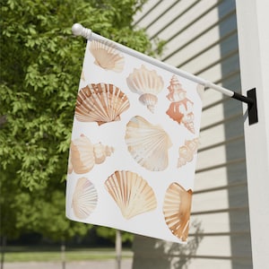 May include: A white flag with a watercolor design of seashells in shades of brown and beige. The seashells are arranged in a random pattern on the flag.