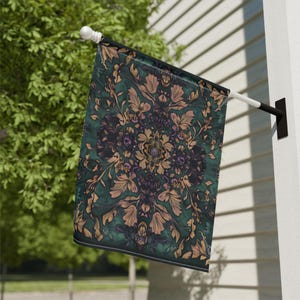 May include: A decorative outdoor flag featuring a detailed floral pattern in shades of green, gold, and purple. The flag is mounted on a white pole and is displayed outside a building.