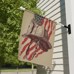 May include: A beige flag featuring a firefighter's helmet superimposed over a distressed American flag design. The helmet is detailed with straps and a badge. The flag is mounted on a white pole and displayed outdoors.
