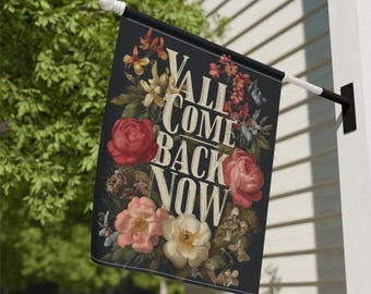 May include: A black outdoor flag with the text "Y'ALL COME BACK NOW" in a vintage font, surrounded by a floral arrangement of red, pink, and cream roses and other flowers.