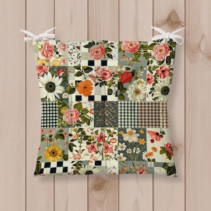 Könnte beinhalten: Ein quadratisches Sitzkissen mit einem Patchwork-Design mit Blumenmustern, darunter Rosen und Sonnenblumen, in Rosa-, Orange- und Weißtönen. Das Kissen hat weiße Bänder an den Ecken, um es an einem Stuhl zu befestigen.