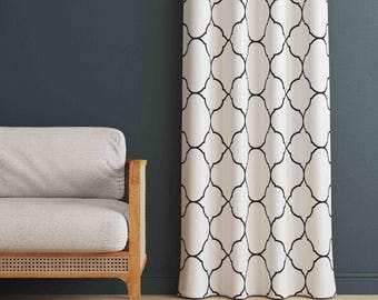 May include: A floor-length curtain featuring a white fabric base with a repeating black quatrefoil geometric pattern. The curtain hangs in vertical folds, displaying a consistent grid of interconnected curved lines across the entire surface.