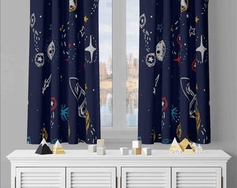 May include: Two dark blue curtains featuring a repeating pattern of white, red, and yellow space-themed illustrations, including rockets, planets, stars, and comets. The curtains hang vertically, displaying a consistent celestial graphic design.