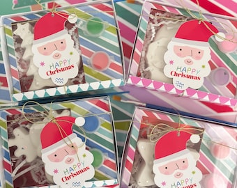 May include: Four clear gift boxes with white and red Santa Claus ornaments, paint pots, and a "Happy Christmas" tag. The boxes are decorated with colorful stripes and are tied with gold ribbon.