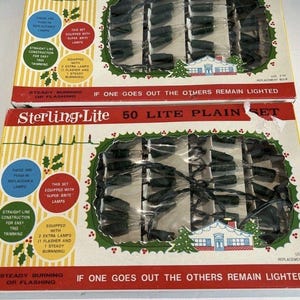 May include: Two vintage Sterling-Lite 50 Lite Plain Set Christmas light boxes. Each box has a red and white design with green accents, and contains a string of green lights. The boxes include text about replaceable lamps and easy tree trimming.