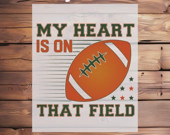 May include: A DTF transfer design with the text "Ready To Press" and "My Heart Is On That Field". The design features an orange football with white stripes and green stitching, along with green and orange stars.