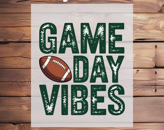 May include: A football-themed graphic with the words "GAME DAY VIBES" in green, featuring a brown football. The words "Ready To Press" and "DTF Transfer" are also included in the design. The background is a wooden texture.