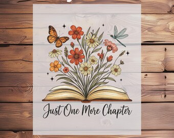 May include: DTF transfer featuring an open book with a floral bouquet, a butterfly, and a dragonfly. The bouquet includes orange, yellow, and pink flowers. The text "Just One More Chapter" is below the book.