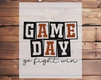May include: A white DTF transfer with the words "GAME DAY" in a black and orange design. The phrase "go fight win" is written below in a script font. The words "Ready To Press" and "DTF Transfer" are at the top and bottom.