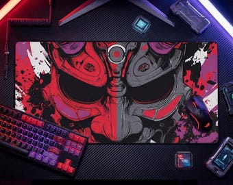 May include: A rectangular gaming mousepad featuring a stylized red and gray oni mask design. The mask is split down the middle, with a splash of red and purple paint. A keyboard and mouse are visible.