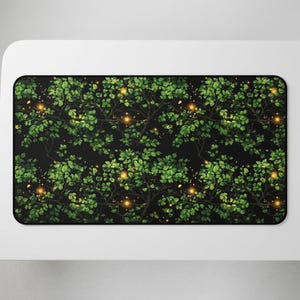 Puede incluir: Alfombrilla de ratón rectangular con un patrón repetido de hojas y ramas verdes sobre un fondo negro. Pequeños orbes amarillos brillantes están dispersos, creando un diseño caprichoso inspirado en la naturaleza.
