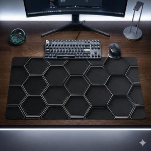 Puede incluir: Alfombrilla de ratón para juegos negra y plateada con un patrón geométrico de panal. La alfombrilla es rectangular y presenta un diseño repetido de hexágonos negros con contornos plateados. Un teclado y un ratón están sobre la alfombrilla.