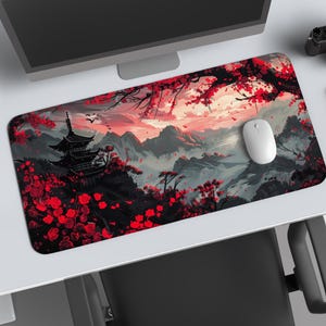 Puede incluir: Alfombrilla de ratón rectangular con un diseño de paisaje japonés. El diseño presenta una pagoda, montañas y flores de cerezo rojas. La paleta de colores incluye rojo, negro, gris y blanco. Un ratón blanco descansa sobre la alfombrilla.