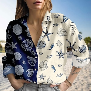 Può includere: Camicia abbottonata a maniche lunghe con design diviso. Un lato è blu navy con motivi di conchiglie e stelle marine bianche, l'altro è bianco sporco con motivi blu.