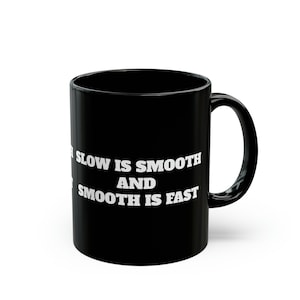 May include: Black ceramic coffee mug with white text that reads "Slow is smooth and smooth is fast".