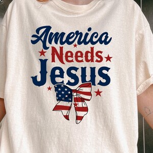America Needs Jesus Comfort Colors T-Shirt, Patriotic Christian Shirt, 4th Of July Faith Tee, Red White Blue Flag Graphic Jesus Shirt