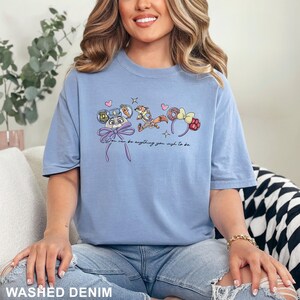 Puede incluir: Camiseta azul claro con personajes de dibujos animados y el texto "You can be anything you wish to be." El dise&ntilde;o incluye un conejito, un zorro y diademas florales. La camiseta est&aacute; hecha de un material suave y c&oacute;modo.