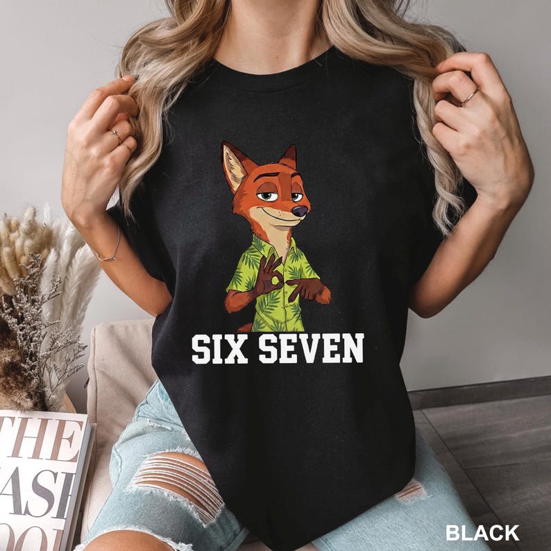 Puede incluir: Camiseta negra con un personaje de zorro de dibujos animados que lleva una camisa hawaiana verde. El texto "SIX SEVEN" est&aacute; impreso en blanco debajo de la imagen. La palabra "BLACK" est&aacute; impresa en blanco en la parte inferior derecha.