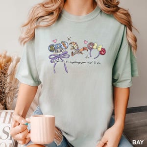 Puede incluir: Camiseta verde claro con dise&ntilde;os de personajes de dibujos animados y el texto "You can be anything you wish to be." El dise&ntilde;o incluye una placa de polic&iacute;a, una zanahoria, un zorro, una rosquilla y una frambuesa.