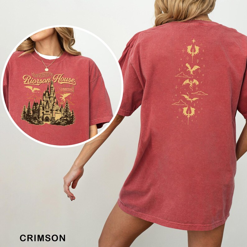 May include: Crimson-colored t-shirt featuring a gold illustration of a castle with the text "Riorison House" and "Aretian". The back of the shirt has a gold design of dragons and clouds. The shirt is a comfortable, oversized fit.