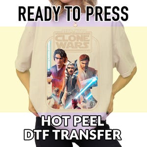 May include: A beige t-shirt featuring a Star Wars: The Clone Wars graphic. The design includes characters with lightsabers and the text "READY TO PRESS" and "HOT PEEL DTF TRANSFER".