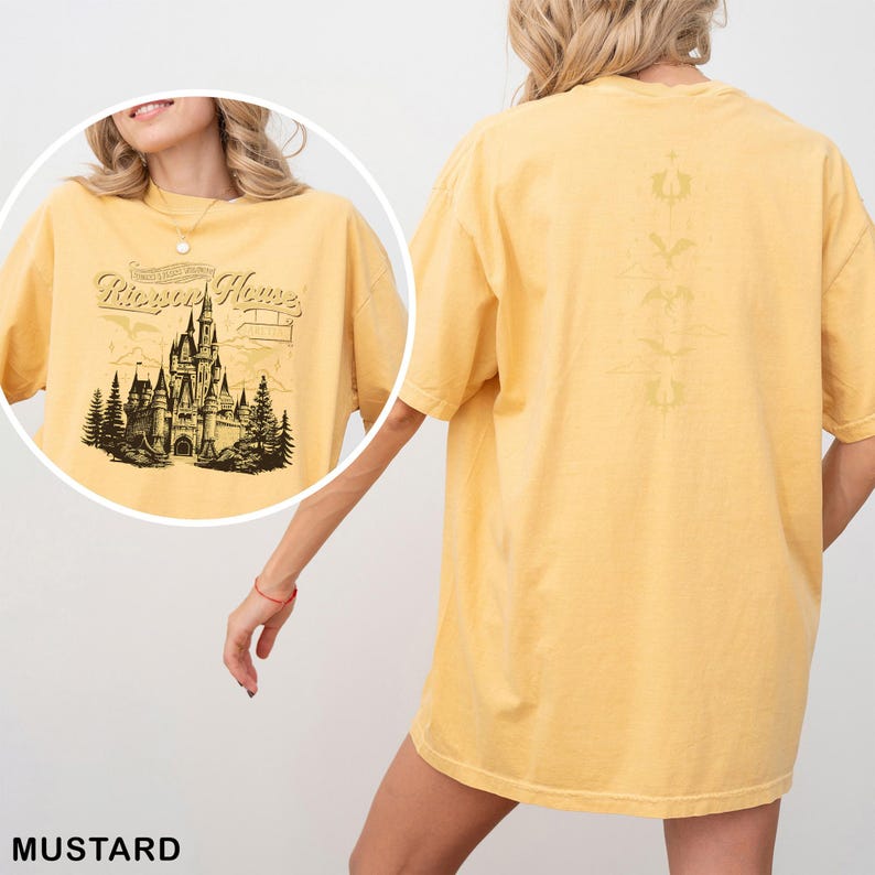 May include: Mustard-colored t-shirt featuring a detailed graphic of a castle with the text "Rhapsody Home" on the front. The back of the shirt has a vertical design. The shirt is a loose fit.