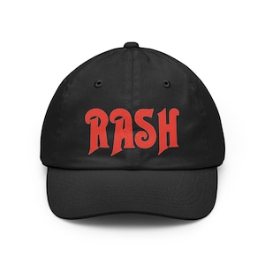 May include: A black baseball cap featuring the word RASH printed in a bold, red, stylized font across the front panels. The cap has a structured crown, a curved brim, and matching black eyelets for ventilation on the top panels.