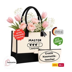 Könnte beinhalten: Eine cremefarbene Tragetasche mit schwarzen Akzenten und Griffen, mit dem Text "MASTER LOADING...", gefüllt mit rosa Tulpen und Schleierkraut. Eine passende Kosmetiktasche ist enthalten. Der Text "Mit gratis Kosmetiktasche!" ist ebenfalls vorhanden.