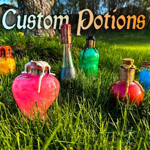 Könnte beinhalten: Eine Sammlung von sechs Glasflaschen, gefüllt mit bunten Flüssigkeiten, mit der Aufschrift "Custom Potions". Die Flaschen sind auf einem Bett aus grünem Gras angeordnet.