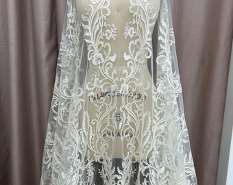 May include: White floral lace fabric with a delicate pattern. The lace is on a sheer mesh background.