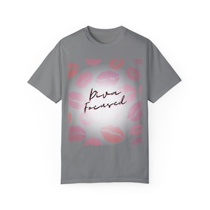 Puede incluir: Camiseta gris con un diseño de estampado de labios rosa y blanco y el texto "Diva Focused" en negro.