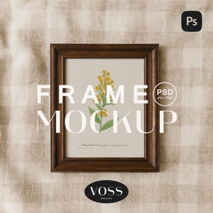 May include: A framed botanical print featuring a yellow flower with green leaves. The frame is dark brown and the print is set against a neutral background. The words "FRAME MOCKUP" are displayed in white. The image also includes the text "VOSS MOCKUPS".