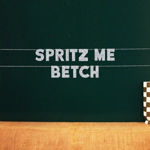 May include: A green chalkboard with the text "SPRITZ ME BETCH" written in silver glitter letters.