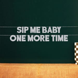 Peut inclure: Une bannière avec le texte "SIP ME BABY ONE MORE TIME" en lettres argentées à paillettes tendues sur un fond vert foncé. Une tasse à carreaux marron et blanche est visible à droite.
