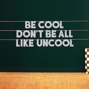 Puede incluir: Una pizarra verde con el texto "BE COOL DON'T BE ALL LIKE UNCOOL" escrito en letras de purpurina plateadas.