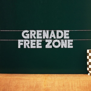 May include: A green chalkboard with silver glitter letters spelling "GRENADE FREE ZONE" hanging from string.