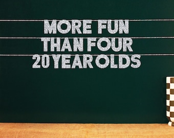 May include: A silver glitter banner with the text "More Fun Than Four 20 Year Olds" hanging on a dark green chalkboard background.