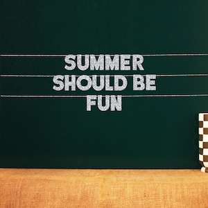 May include: A dark green chalkboard with the words "SUMMER SHOULD BE FUN" in silver glitter letters. Three white lines are drawn across the board. A brown and white checkered mug sits on a burlap surface.