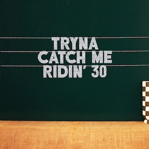 May include: Silver glitter letters spelling "Tryna Catch Me Ridin' 30" on a dark green chalkboard background.