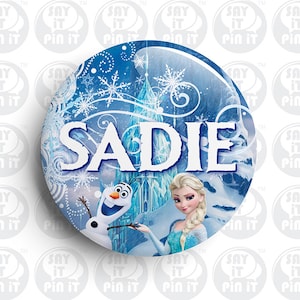Può includere: Un bottone rotondo con un tema Frozen in blu, bianco e azzurro. Il bottone presenta Olaf ed Elsa del film Frozen. Il testo "SADIE" è in lettere bianche su uno sfondo blu.