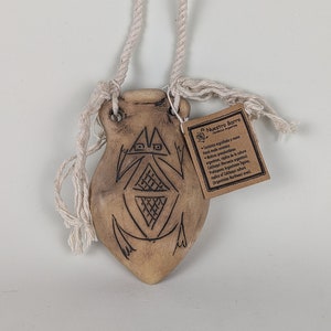 Könnte beinhalten: Ein kleiner, brauner Keramiktopf mit einem Seilhenkel. Der Topf hat ein geometrisches Muster, das in die Oberfläche eingeätzt ist. Der Topf ist mit "Nuestro Barro Ceramica Argentina" beschriftet.